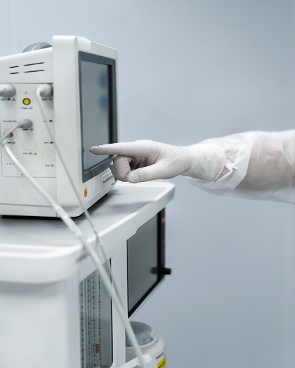 Profesional de salud con guante clínico maneja un equipo médico con sonda conectada.